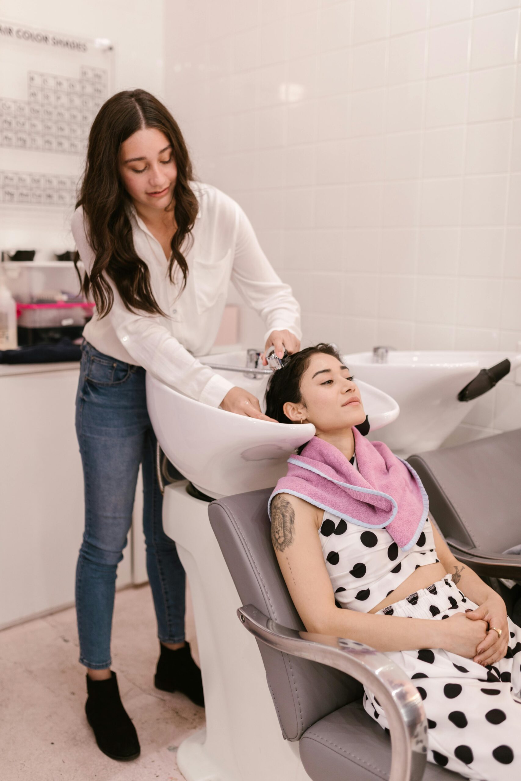 A hair stylist washing a female client's hair at a salon, showcasing a relaxing and professional experience.